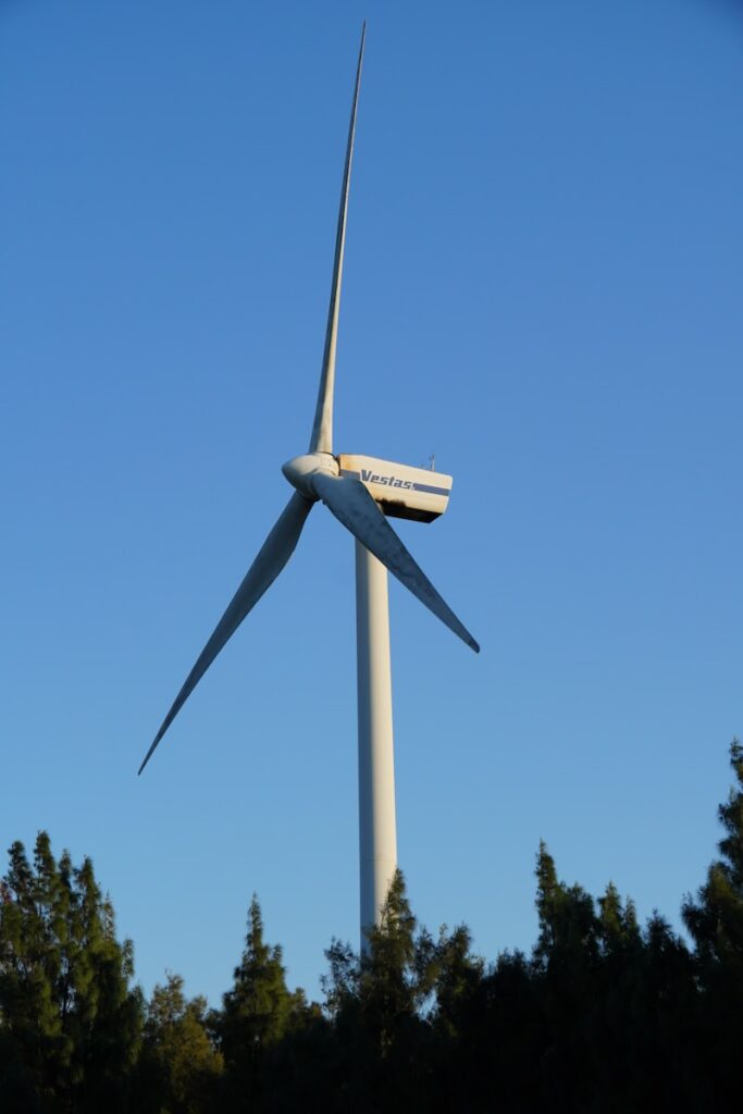 A white wind turbine against a clear blue sky.